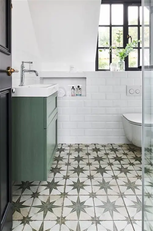 ванная комната с белыми стенами, выложенными плиткой метро, зеленой подвесной тумбой и энкаустической плиткой на полу
