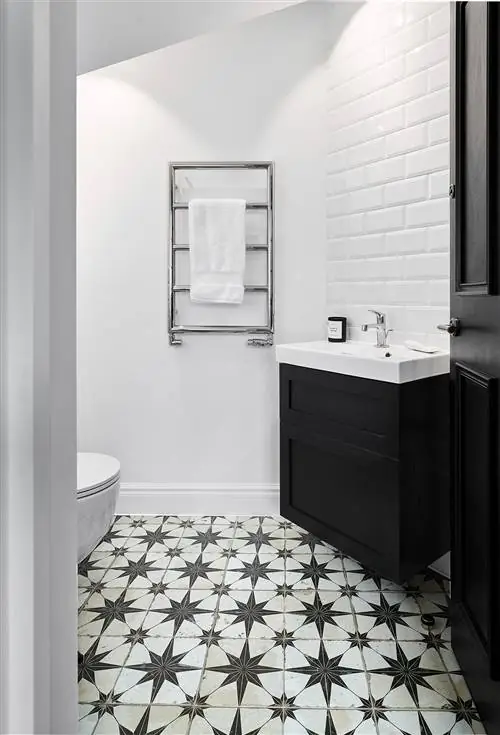 черно-белая ванная комната с подвесным шкафом для раковины и звездным кафельным полом