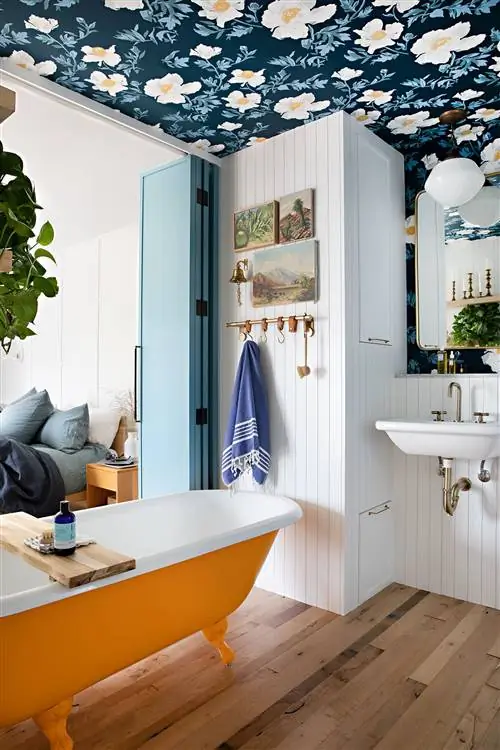 Ванная комната в стиле ретро с желтой ванной на ножках, цветочными обоями на потолке и синими двустворчатыми дверями