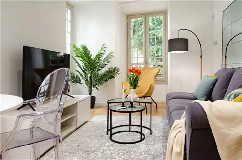 гостиная в элегантном стиле, украшенная растениями и горчичным бархатным креслом