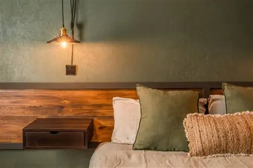 спальня с изготовленным на заказ деревянным изголовьем и стеной с зелеными обоями