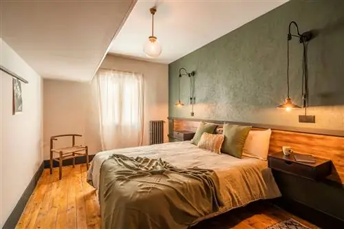 спальня с изготовленным на заказ деревянным изголовьем и стеной с зелеными обоями