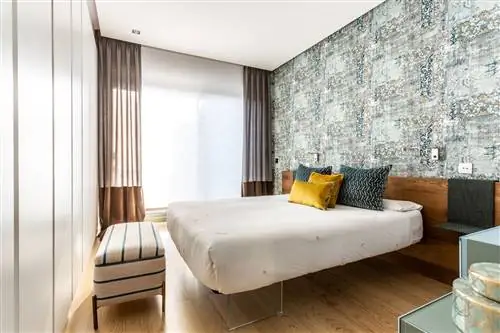 спальня с изготовленным на заказ деревянным изголовьем и состаренными обоями