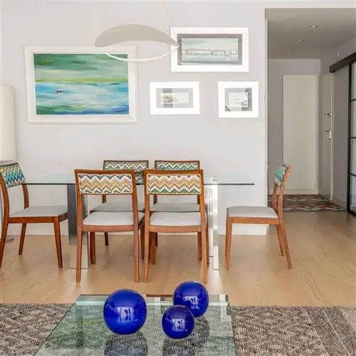 современная столовая со стеклянным столом и деревянными стульями и зигзагообразной обивкой