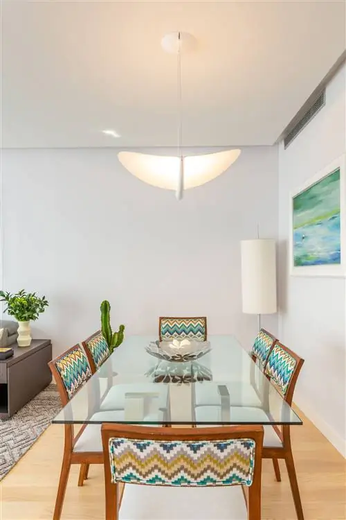 современная столовая со стеклянным столом и деревянными стульями и зигзагообразной обивкой