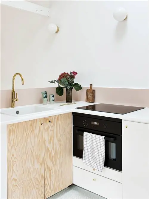 открытая кухня в л с натуральным деревом и белыми шкафами, розовым фасадом и золотым краном