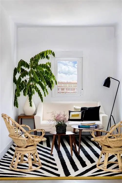 гостиная с белым диваном, двумя креслами из ротанга, деревянными столиками и ковром в черно-белую полоску