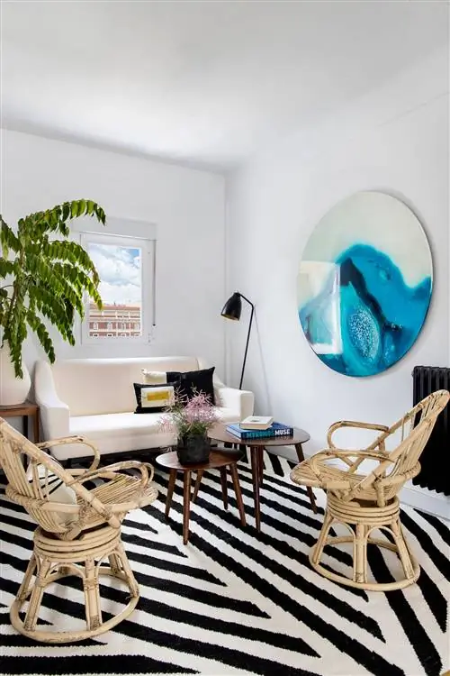 гостиная с белым диваном, двумя креслами из ротанга, деревянными столиками и ковром в черно-белую полоску