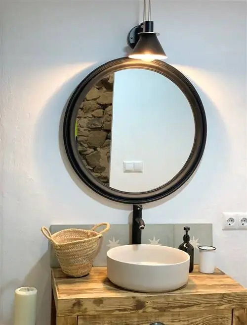 ванная комната с деревянной тумбой и круглым зеркалом в черной раме
