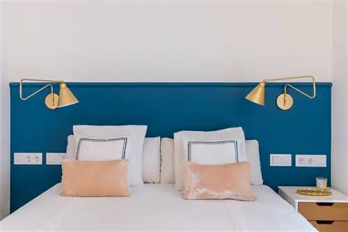 спальня с изголовьем, выкрашенным в синий цвет, и золотыми бра