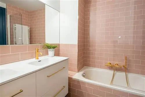 ванная комната с ванной, розовой плиткой в стиле метро и подвесными белыми шкафчиками