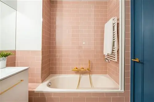 ванная комната с ванной, розовой плиткой в стиле метро и подвесными белыми шкафчиками