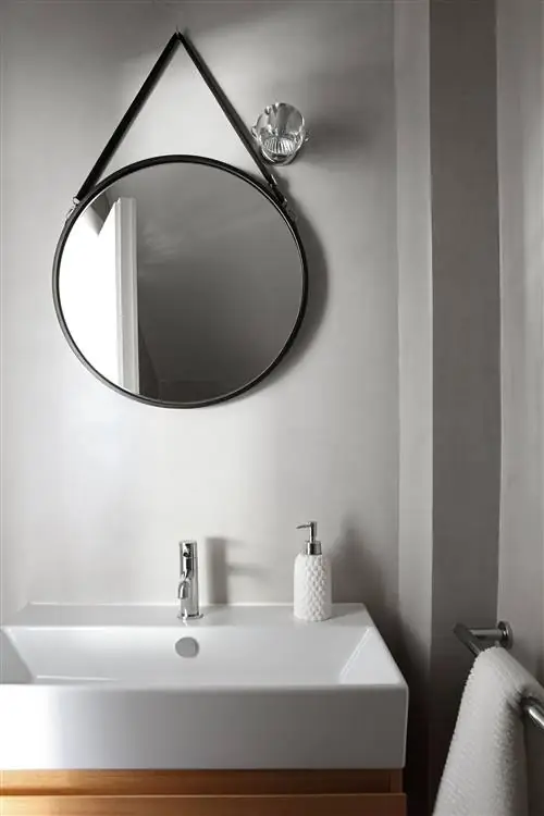 гардеробная со встроенной белой раковиной и круглым зеркалом