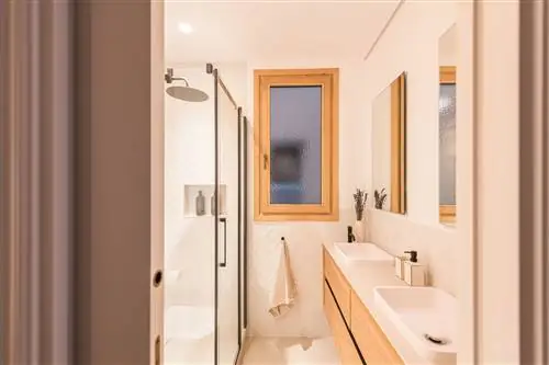 ванная комната с белой плиткой в елочку и подвесным деревянным шкафом