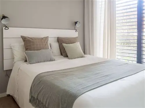 спальня с белым деревянным изголовьем и бра промышленного дизайна