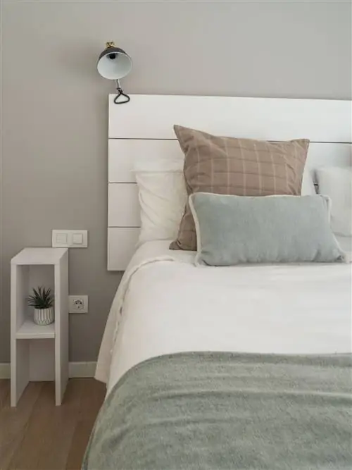 спальня с белым деревянным изголовьем и бра промышленного дизайна