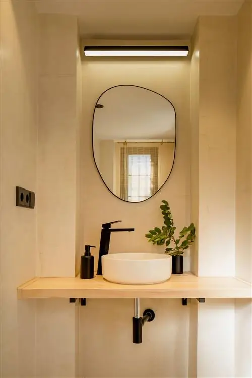 унитаз с деревянной полкой, черным матовым краном и органическим зеркалом