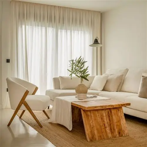 гостиная украшена деревянной мебелью и натуральными волокнами, белым диваном и креслом