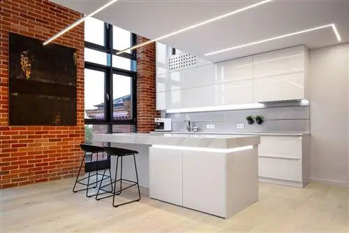 белая кухня открытой планировки с центральным островом и открытой кирпичной стеной