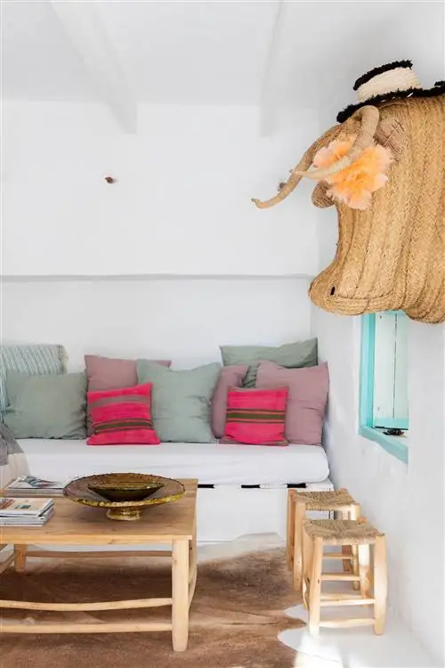 Средиземноморская гостиная с белой встроенной скамейкой, деревянным журнальным столиком и табуретками из дерева и волокна