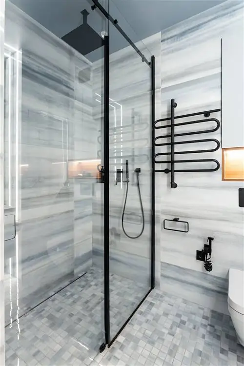 современная ванная комната с мраморной облицовкой и душевой кабиной с фиксированной перегородкой