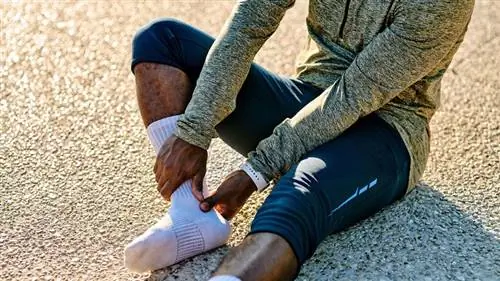 бегун смотрит на ногу в носках