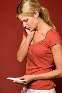 Молодая женщина ломает голову над тестом на беременность