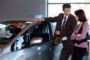 Продавец автомобилей показывает покупателю автомобиль.