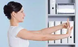 женщина делает растяжку запястья на работе