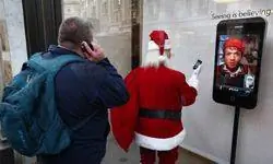 Мужчина смотрит на фигурку Санта-Клауса с iPhone в магазине Apple Store на Риджентс-стрит в Лондоне, Англия.