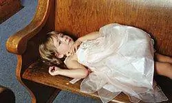 ребенок дремлет на церковной скамье