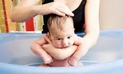 Мать купает младенца