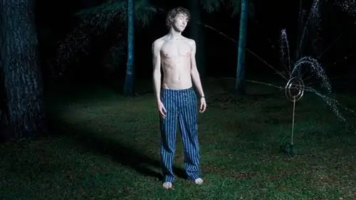 Человек во сне ходит по лужайке.