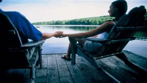 Пара отдыхает в креслах Adirondack Пара отдыхает в креслах Adirondack