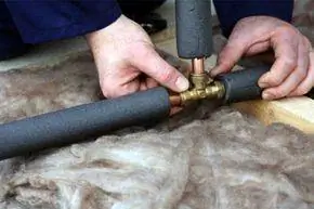 сантехник работает с медными водопроводными трубами