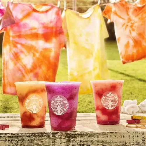 3 новых Starbucks Frozen Refreshers сидят бок о бок с рубашками с принтом тай-дай на заднем плане