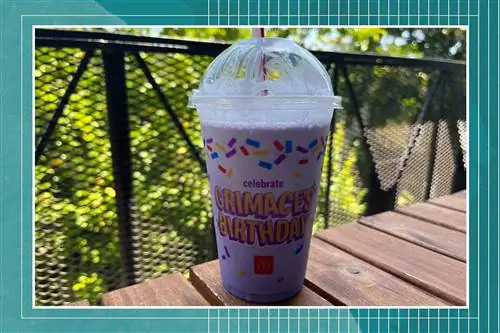 McDonald's Grimace трясет на столе на открытом воздухе с синей рамкой McDonald's Grimace трясет на столе на открытом воздухе с синей рамкой