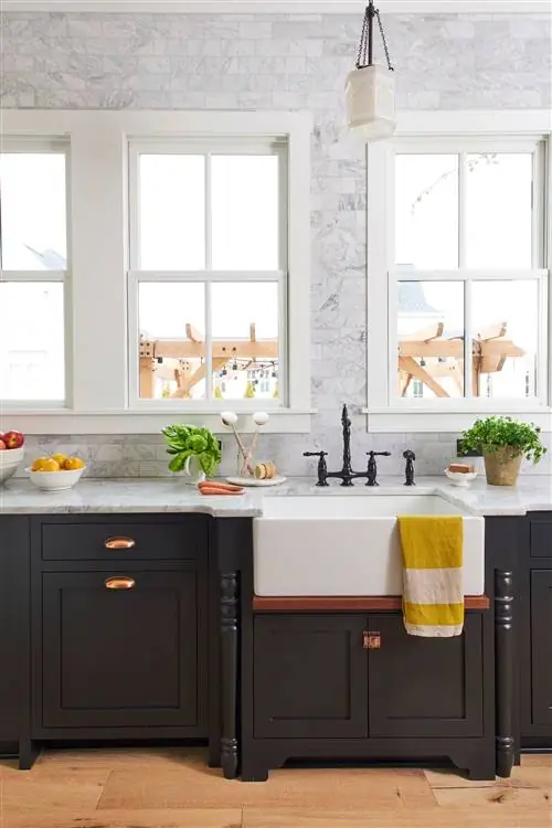 Кухонная раковина с черными шкафами и плиткой на стене с окнами.