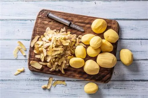 Разделочная доска с очищенным картофелем и картофелечисткой