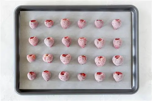 целая замороженная клубника на противне, застеленном пергаментом