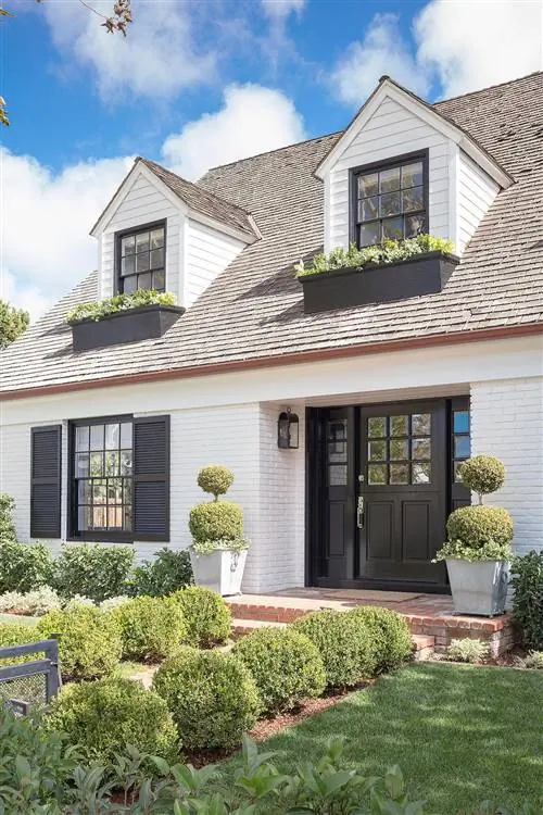 фасад из кирпича, окрашенного в белый цвет, с черной входной дверью и ставнями