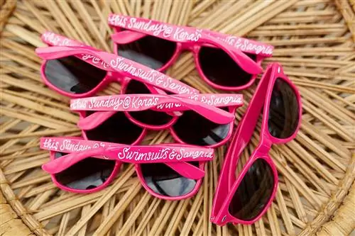 розовые солнцезащитные очки с надписью на столе из ротанга