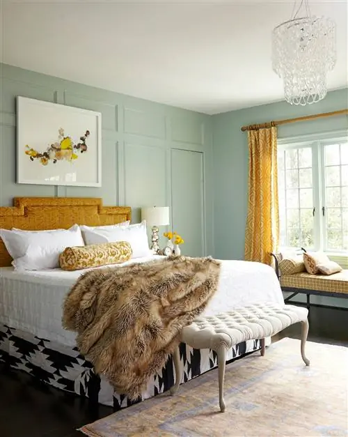 серовато-зеленая комната с желтыми акцентами, меховым покрывалом и люстрой