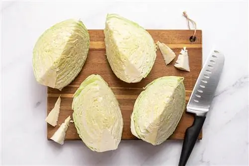 зеленая капуста, нарезанная дольками кухонным ножом на деревянной разделочной доске