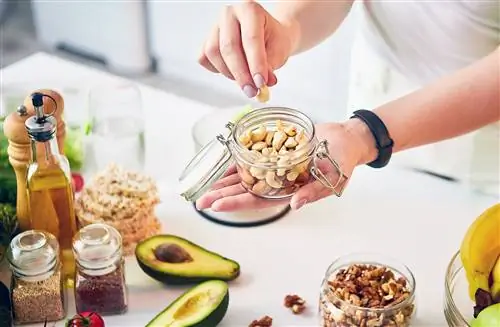 человек ест здоровую закуску из орехов кешью на кухне человек ест здоровую закуску из орехов кешью на кухне