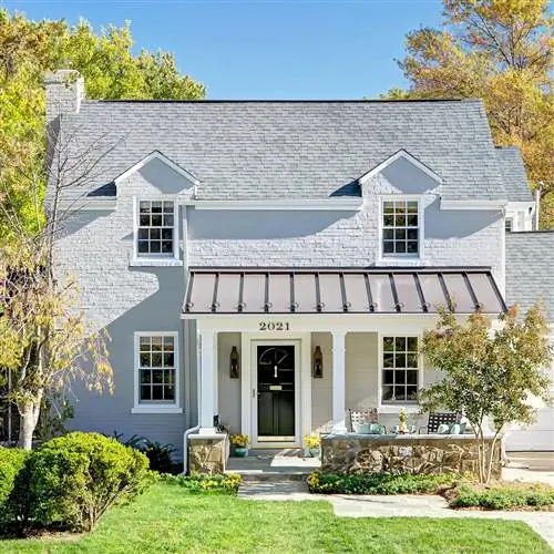 фасад из окрашенного светло-серого кирпича с белыми колоннами и черной входной дверью