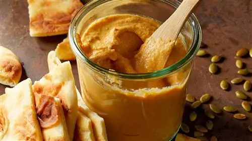 банка соуса из тыквы и тахини с деревянной ложкой и треугольниками лаваша сбоку