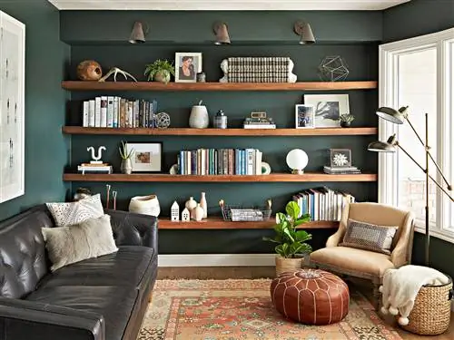 темно-зеленые стены гостиной с открытыми деревянными стеллажами