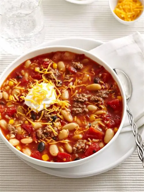Летний чили в белой миске с сыром и сметаной