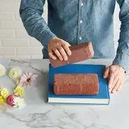 кирпичи и книга в синем переплете, используемые для прессования цветов